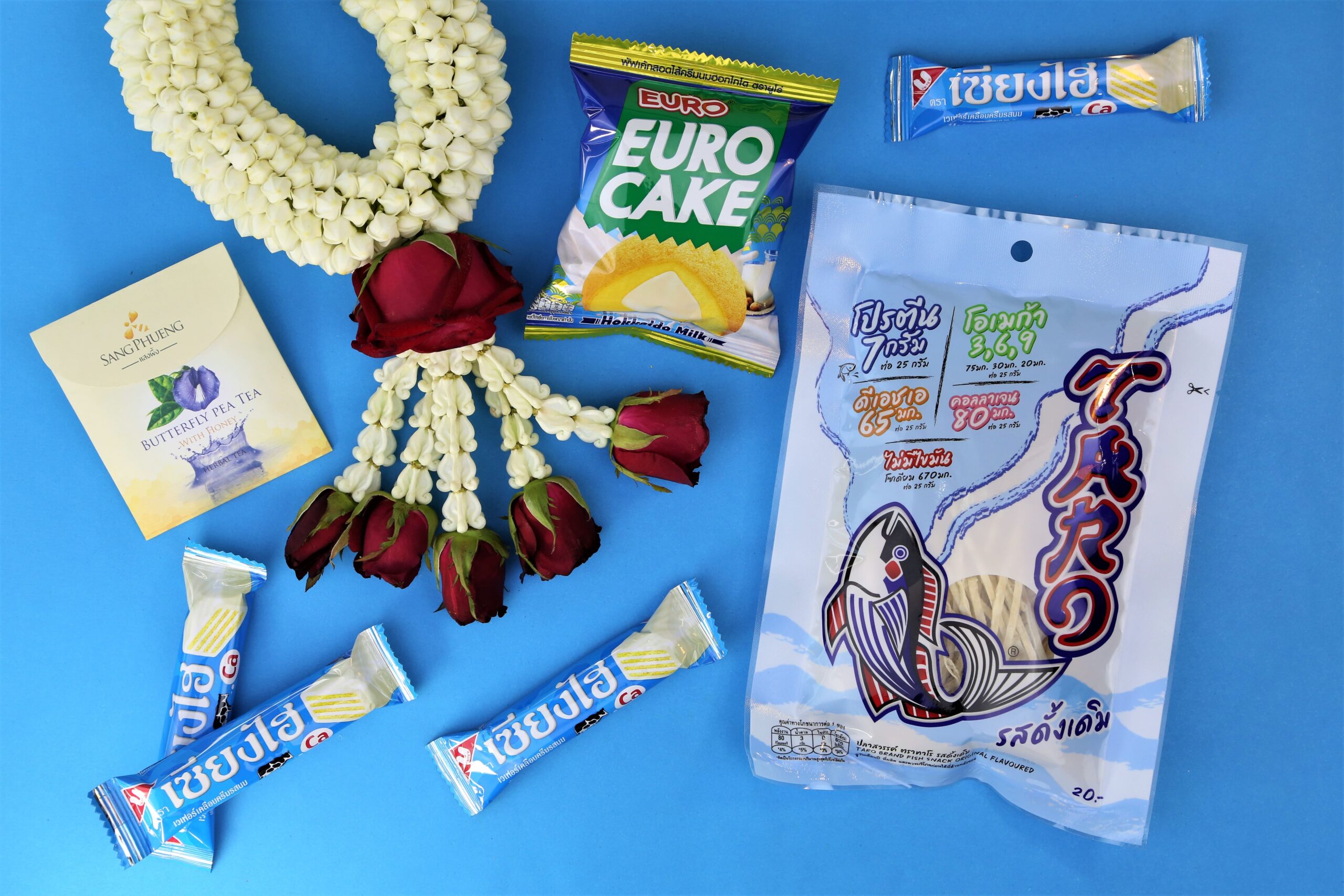Thai snacks with blue packagings and flower garland representing Thai mother's day